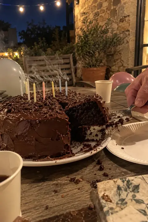 Tarta de chocolate casera con las velas recién sopladas en la mesa de un patio por la noche